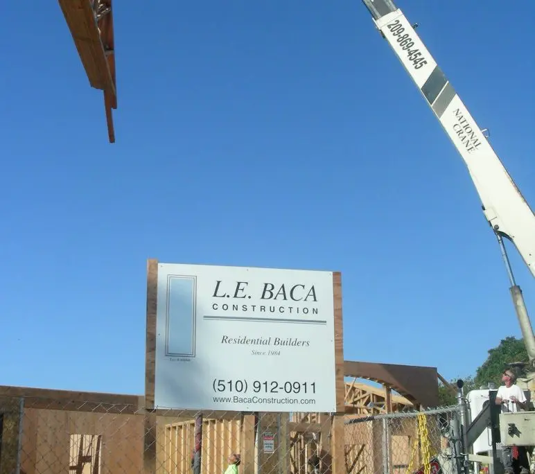 Crane lifting roof trusses at L.E. Baca Construction residential building site