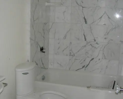 Modern marble-finished bathroom interior by L.E. Baca Construction with bathtub and toilet installation