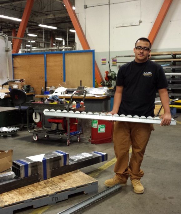 Construction worker holding light fixture inside workshop at L.E. Baca Construction facility