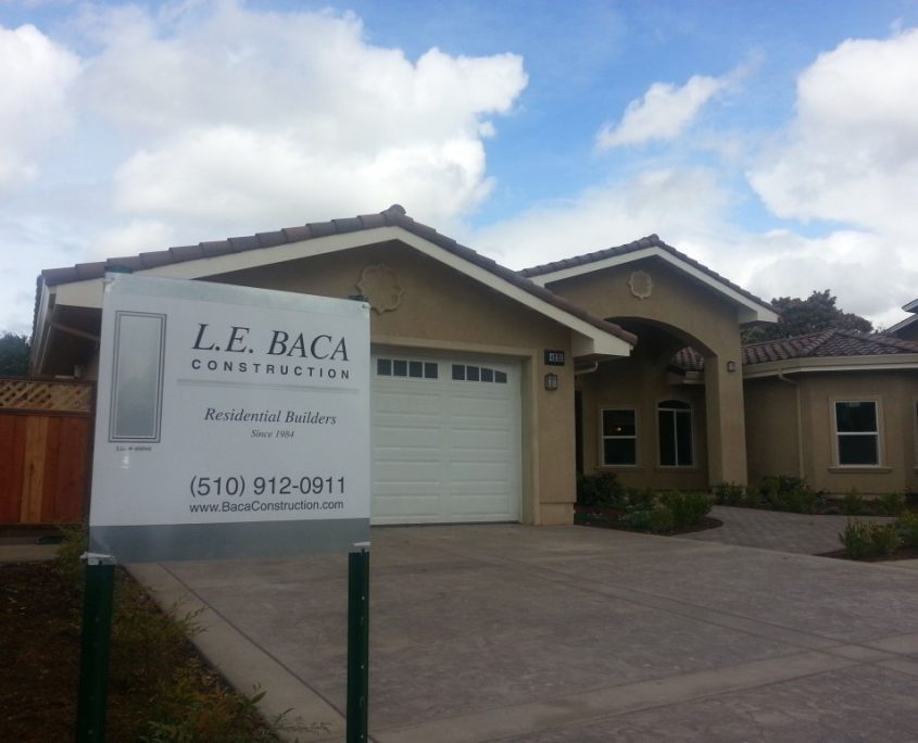 Newly constructed modern home with L.E. Baca Construction sign in front driveway