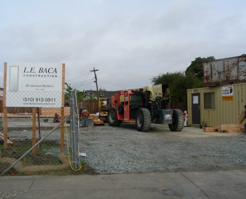 L.E. Baca Construction job site entrance with signage, heavy machinery, and storage container