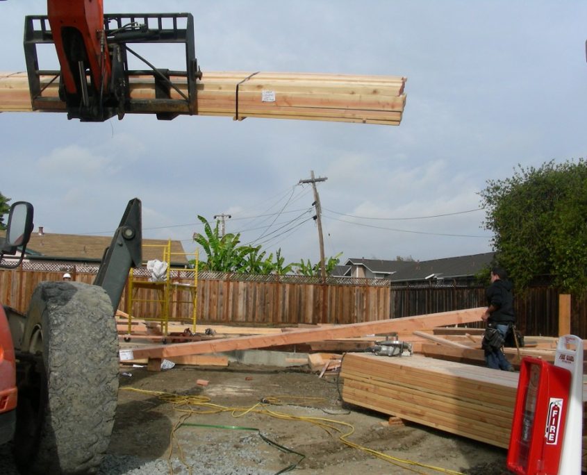L.E. Baca Construction site with forklift lifting lumber and worker preparing framing materials