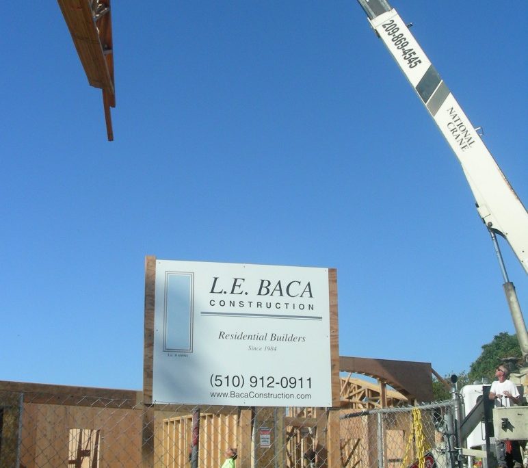 Crane lifting roof trusses at L.E. Baca Construction residential building site