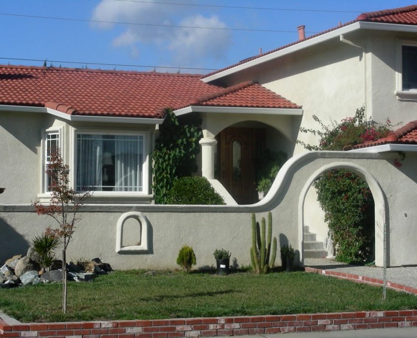 Stucco exterior home with red tile roof and arched entryway by L.E. Baca Construction