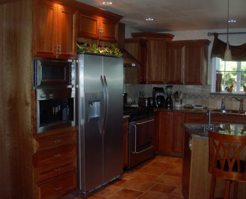 Newly constructed kitchen featuring custom wood cabinetry, stainless steel appliances, built-in coffee station, and Granite Island with bar seating