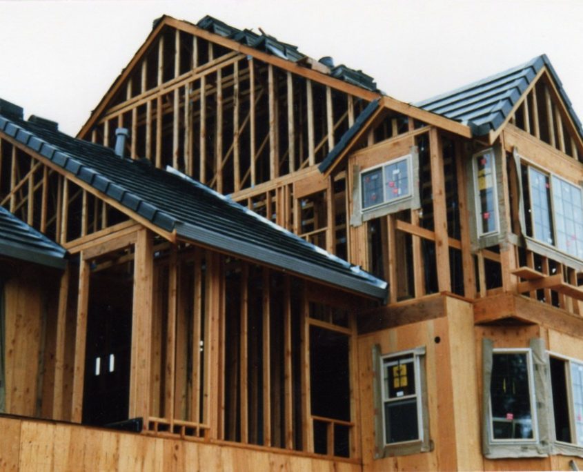 New home construction showing plywood sheathing, wooden studs, and new dark roof tiles