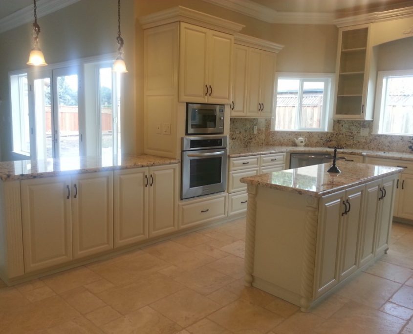 Modern kitchen with off-white or cream-colored cabinets, granite countertops, stainless steel appliances, a center island, and light-colored tile flooring